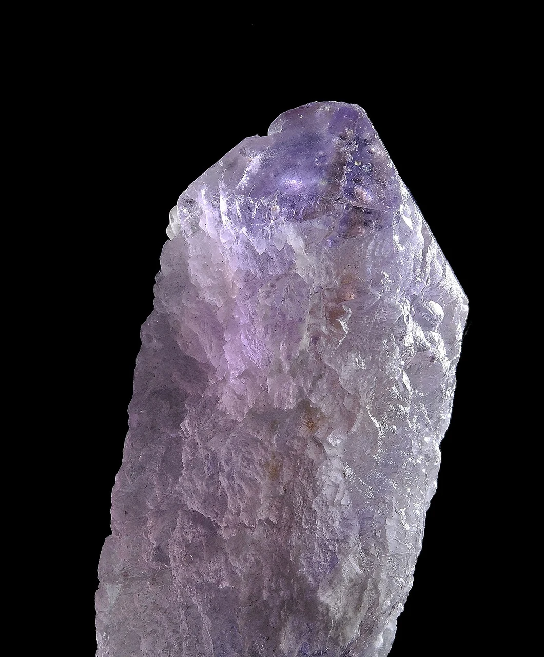 Rough ametrine crystal against a black background
