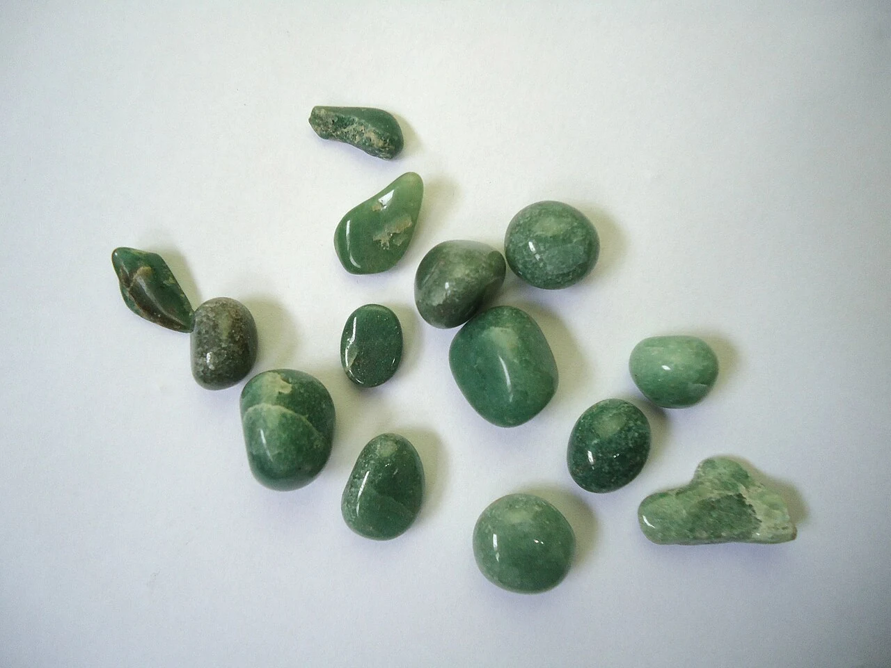 Green tumbled aventurine stones on a light background