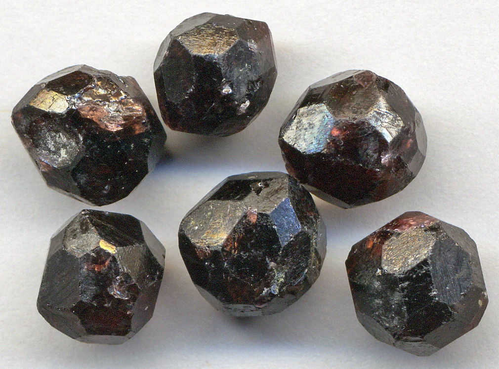 Almandine garnet crystals from Garnet Ledge, Alaska, USA, each about 8 mm across, with many-faced, nearly rounded shapes.