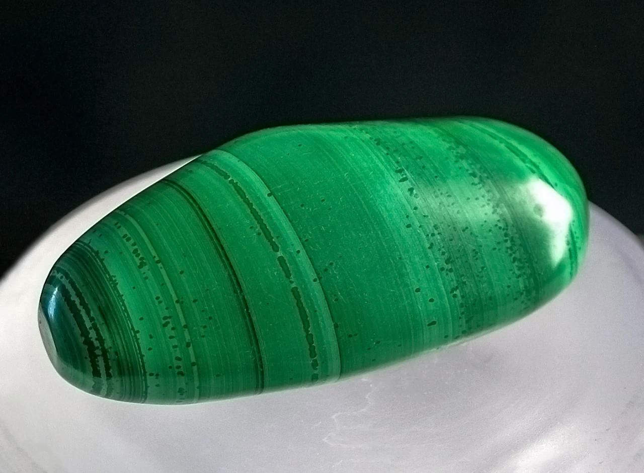 Polished green malachite with darker parallel bands.