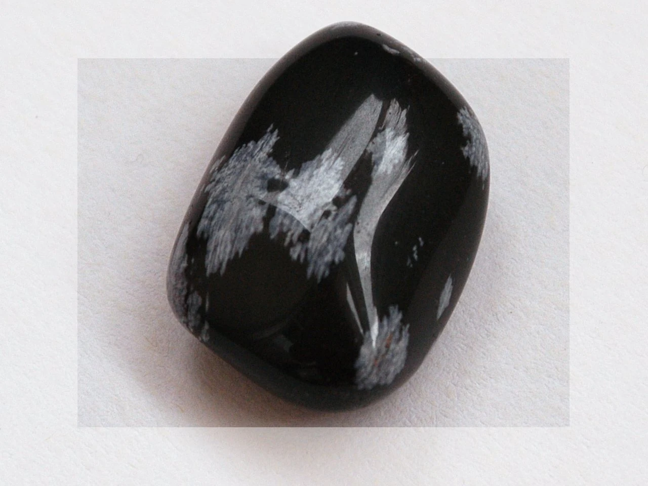Polished black snowflake obsidian with pale radiating patterns.