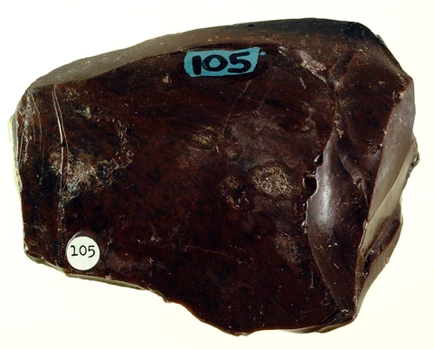 Brown obsidian specimen from a geological collection, with a shiny glass surface.