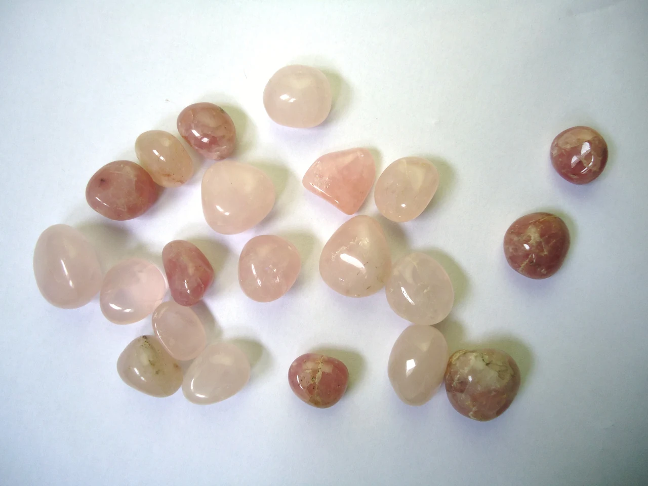Polished rose quartz pebbles showing varying pink shades and cloudiness.